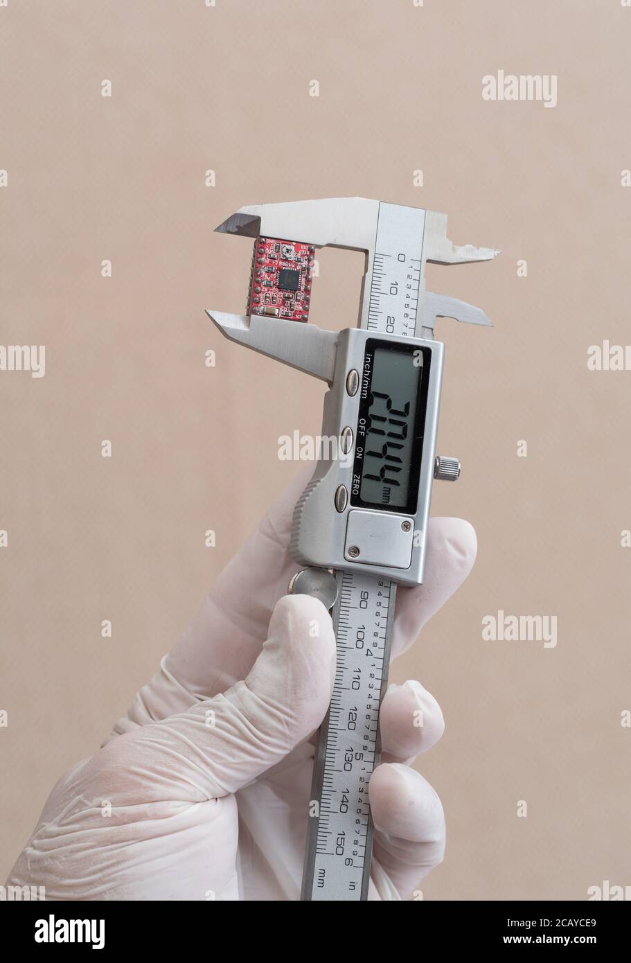 Man misst einen Mikrochip mit elektronischem Präzisionssattel, nur Hände, extreme Nahaufnahme. Stockfoto