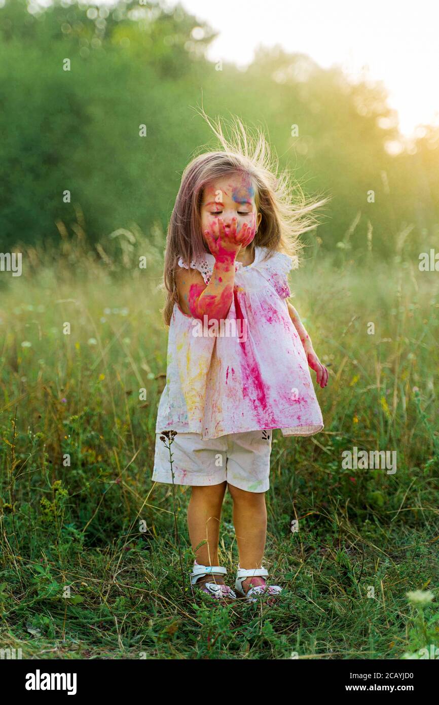 Das kleine Mädchen war mit holi-Farbe bedeckt. Ein Mädchen in einer grünen Lichtung. Haare auf Stockfoto