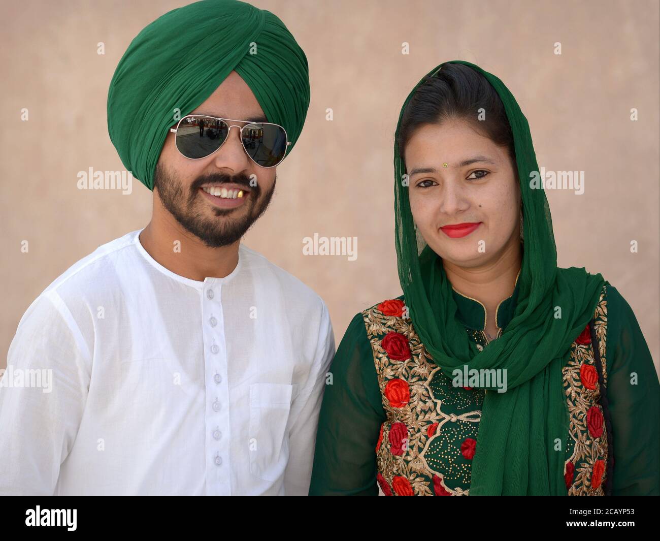 Das modebewusste junge indische Sikh-Paar trägt passende Outfits in Grün und Posen für die Kamera. Stockfoto