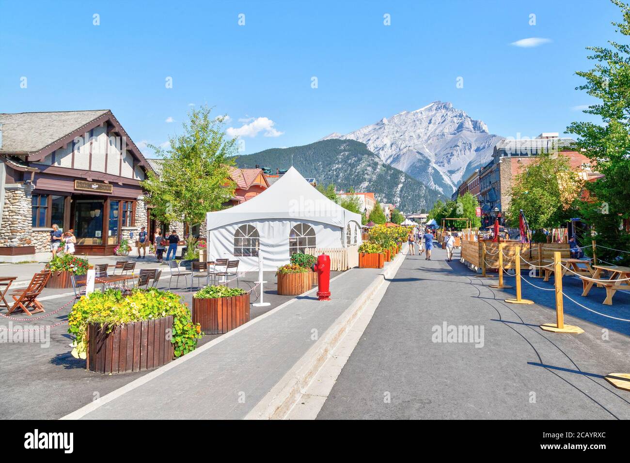 BANFF, KANADA - 29. JULI 2020: Touristen wandern entlang der Banff Avenue im Banff National Park mit Cascade Mountain im Hintergrund. Die Straße war geschlossen Stockfoto