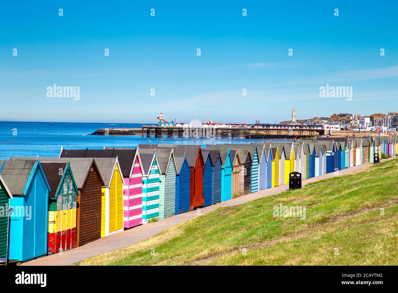 Bunte Strandhütten und Herne Bay Pier in Herne Bay, Kent, Großbritannien Stockfoto