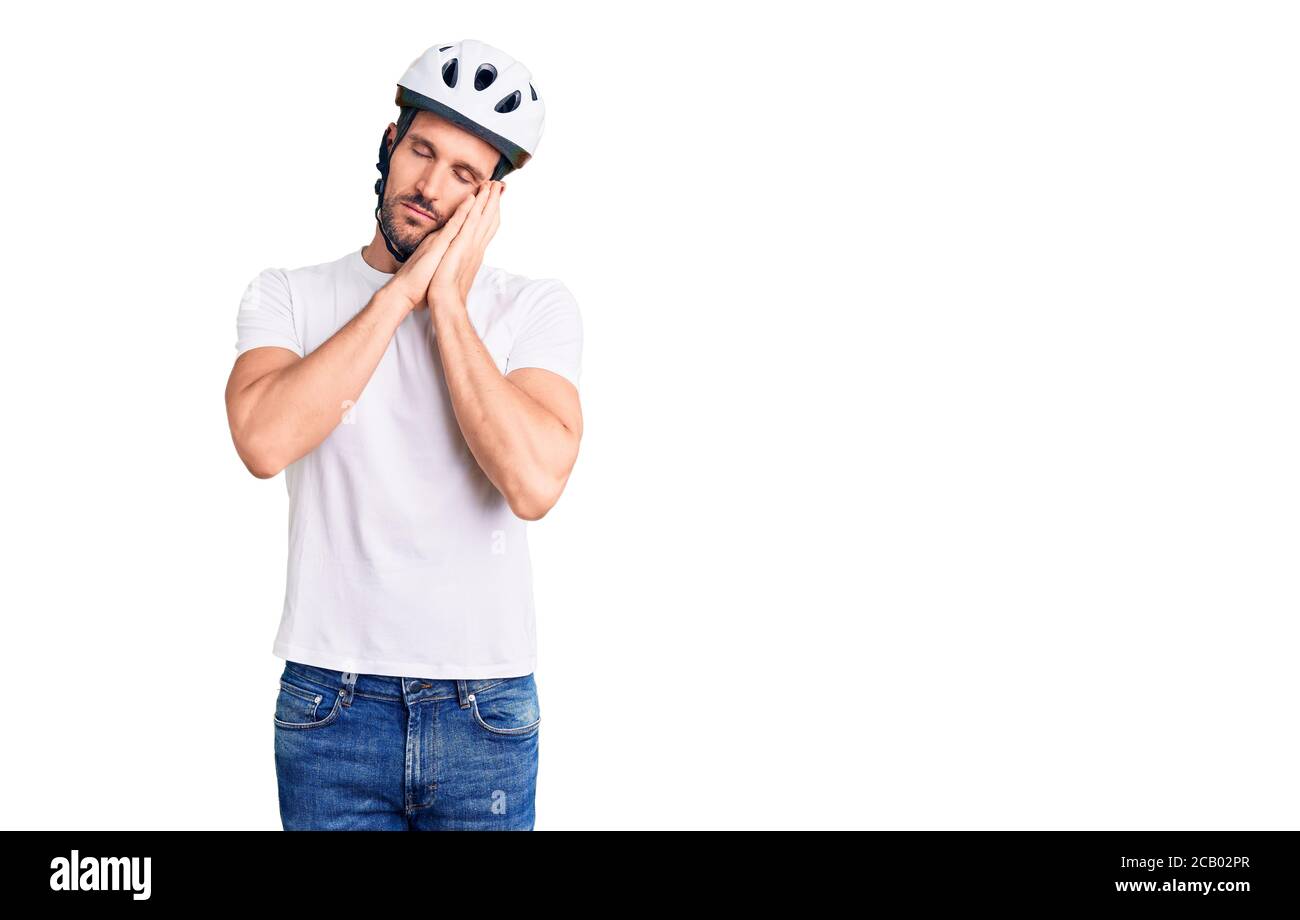 Junger schöner Mann mit Fahrradhelm müde schlafen träumen und posieren mit den Händen zusammen, während lächelnd mit geschlossenen Augen. Stockfoto