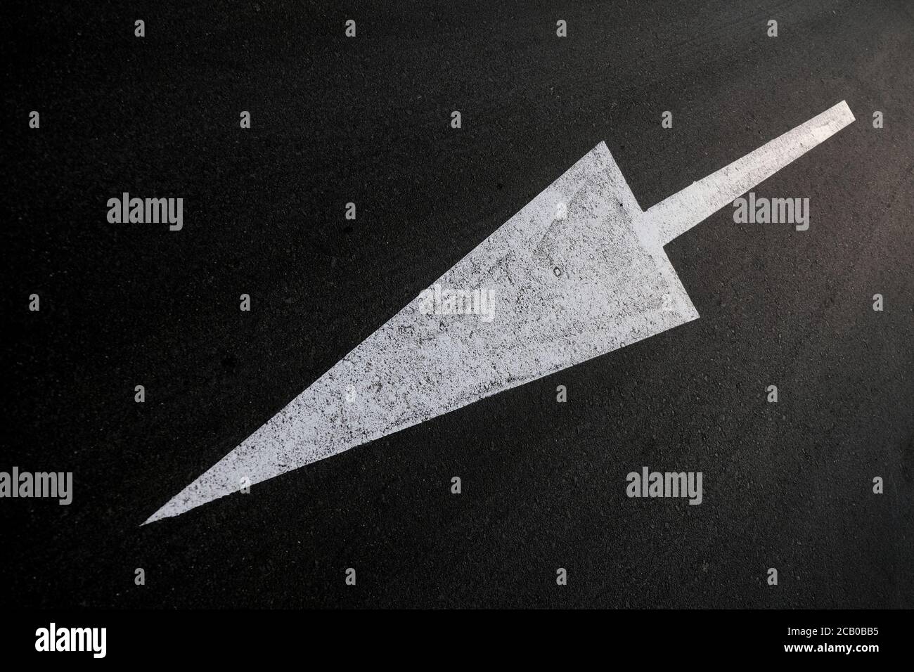 Langer weißer Pfeil auf schwarzem Hintergrund, diagonale Komposition, abgewinkelte Perspektive, horizontaler Rahmen. Stockfoto