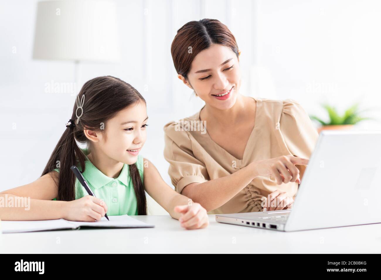 Mutter mit Tochter, die den Laptop beobachtete und zu Hause arbeitete Stockfoto