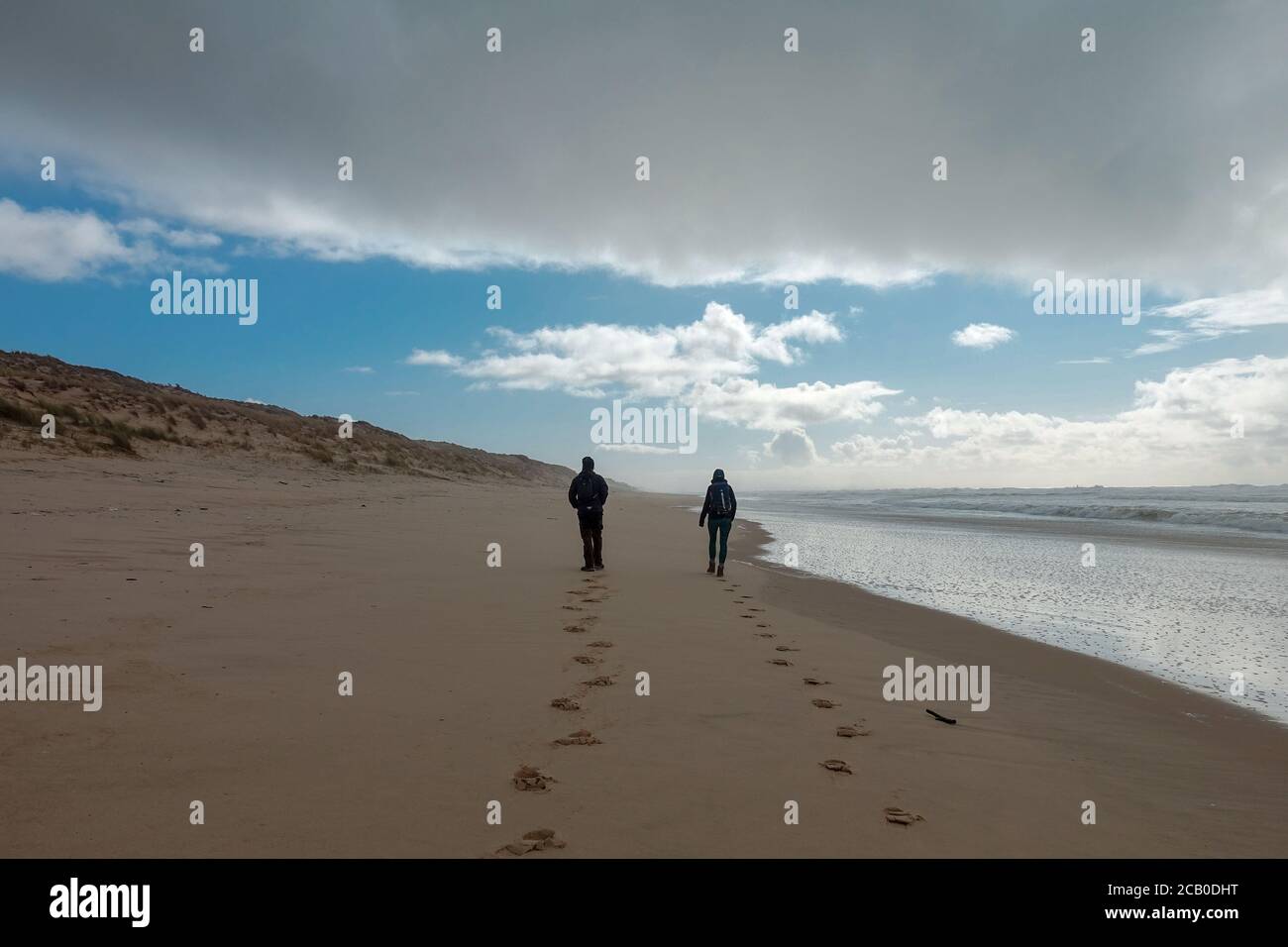 Zwei Personen zu Fuß am Ocean Beach an der Atlantikküste von Frankreich in der Nähe von Lacanau-Ocean, Bordeaux, Frankreich. Windiger und wolkiger Wintertag 2020 Stockfoto