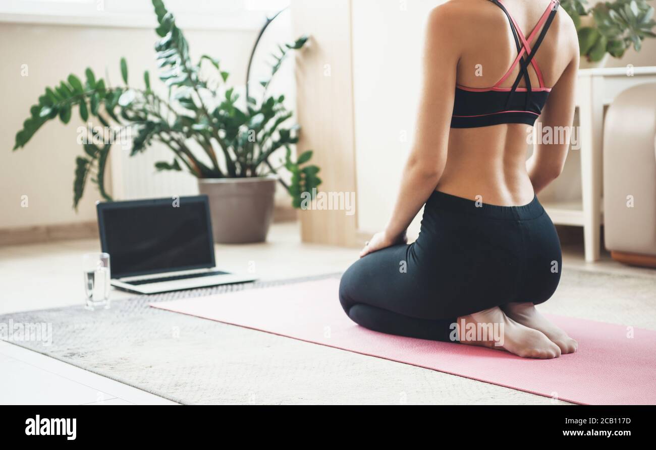 Rückansicht Foto einer kaukasischen Frau in aktiver Kleidung Mit einem Laptop auf dem Boden Fitness tun Stockfoto