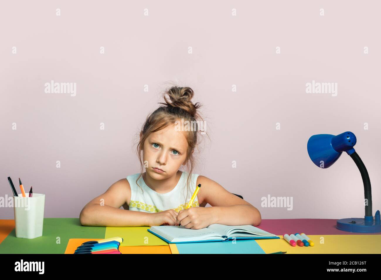 Lustige kleine Mädchen studieren. Profil von kleinen Mädchen zu Hause schreiben. Unglücklich Schulkind Zeichnung. Stockfoto
