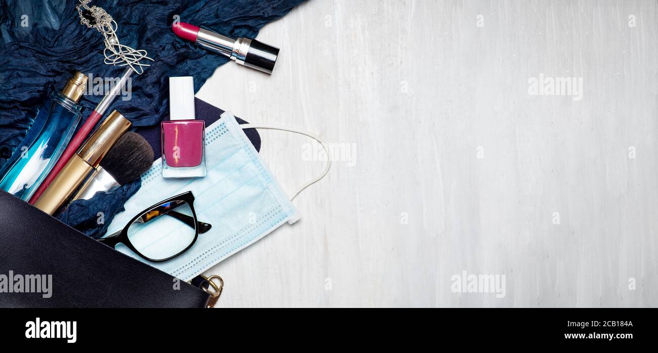 Chirurgische Gesichtsmaske mit verschiedenen Make-up und kosmetische Produkte fallen Aus einer weiblichen Tasche Tischplatte flach mit Kopie legen Platz Stockfoto