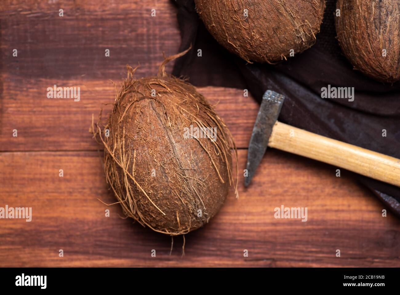 Öffnen Sie Kokosnussfrucht und einen kleinen Hammer auf ein hölzernes Tabellenansicht von oben Stockfoto