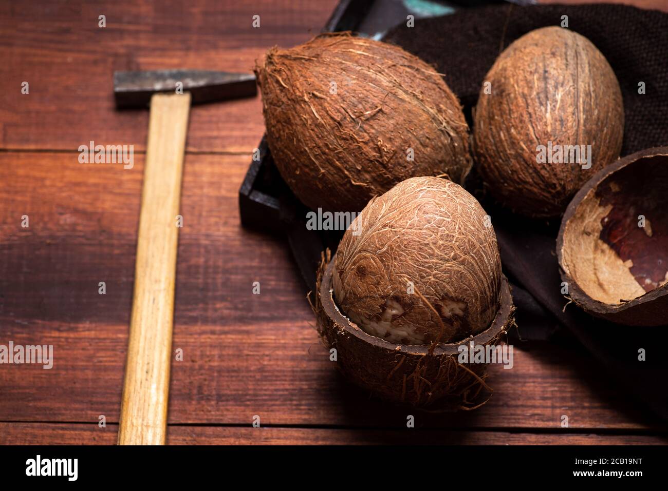 Öffnen Sie Kokosnussfrucht und einen kleinen Hammer auf ein hölzernes Tabellenansicht von oben Stockfoto