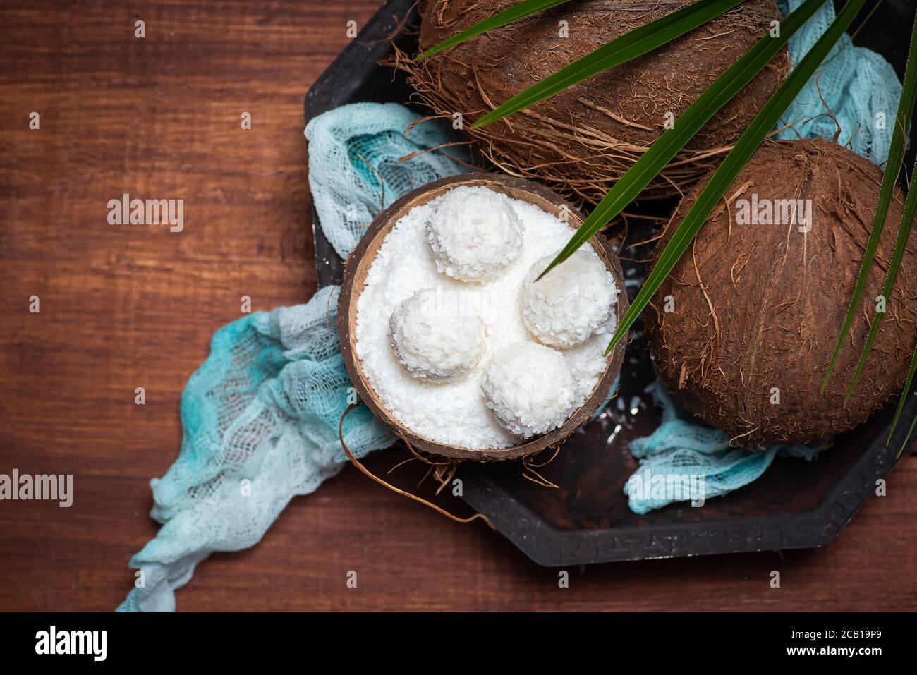 Öffnen und geriebenen Kokosnuss Obst auf einem Holztisch mit Kokosnuss Dessert Bälle Draufsicht Stockfoto