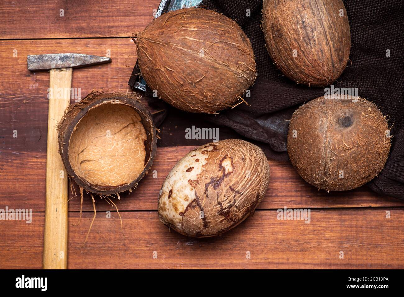 Öffnen Sie Kokosnussfrucht und einen kleinen Hammer auf ein hölzernes Tabellenansicht von oben Stockfoto