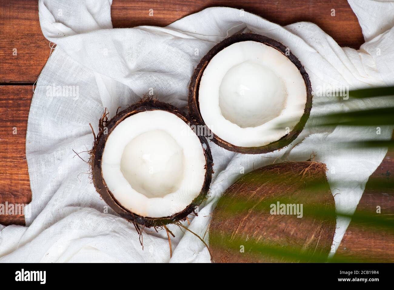 Halbierte offene Kokosnussfrüchte auf einem Holztisch Draufsicht Stockfoto
