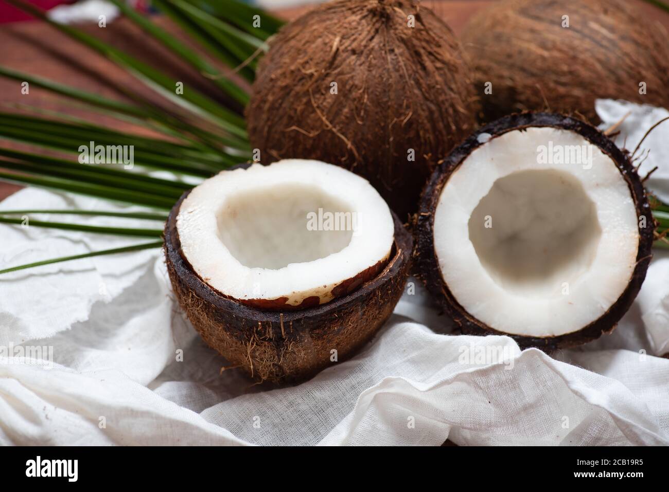 Halbierte offene Kokosnussfrüchte auf einem Holztisch Draufsicht Stockfoto