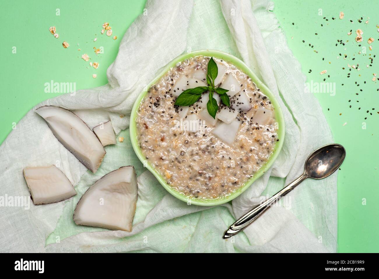 Haferflocken Haferbrei mit geriebener Kokosnuss und Chiasamen in einem Grüne Schüssel Draufsicht Stockfoto
