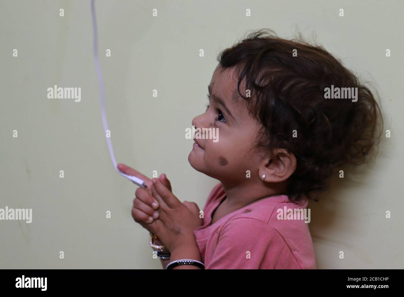 Ein schönes kleines Kind hält das weiße Ladekabel in Seine beiden Hände beim Testen Stockfoto