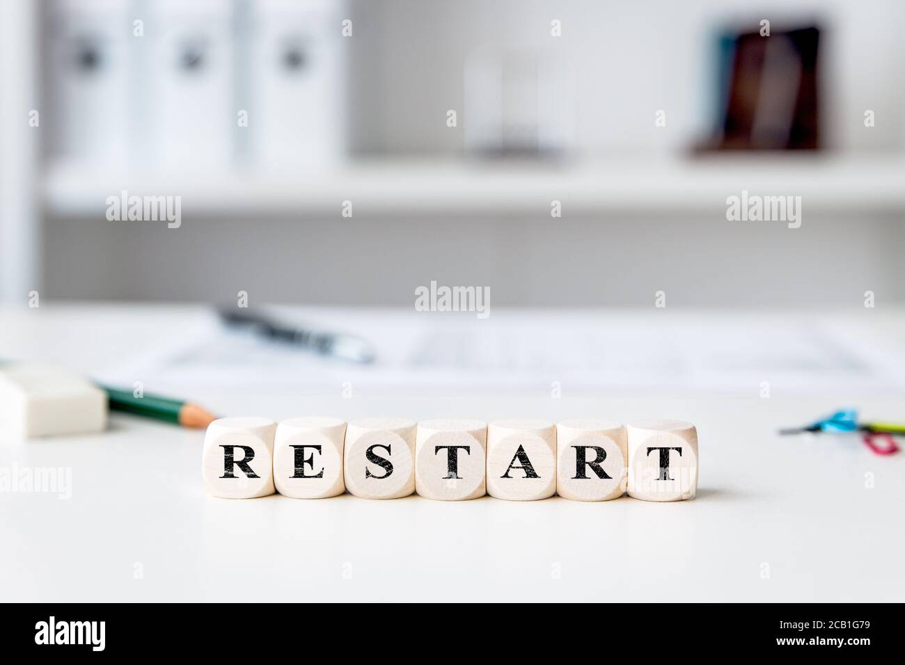 Würfel mit Wort Neustart, Business-Arbeitsplatz im Hintergrund, neue Firma oder Karriere nach der Zeit der Corona und covid-19 Pandemie Stockfoto