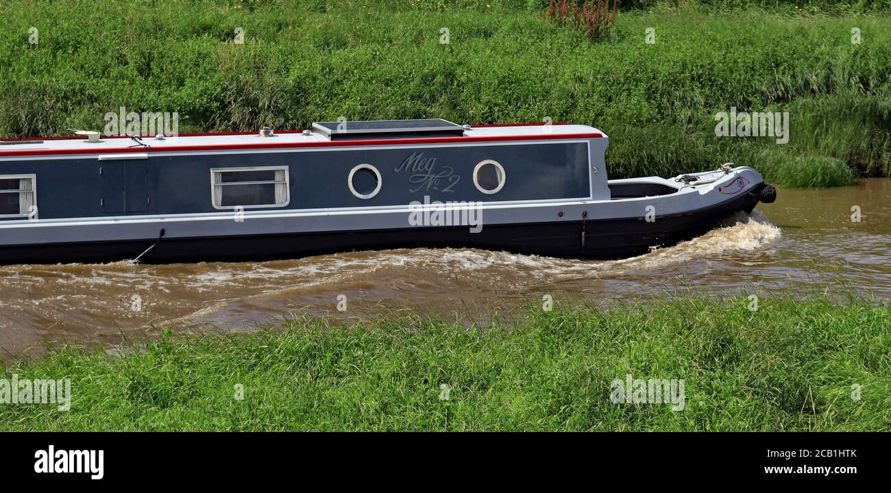 Ein graues und kastanienbraunes Kanalschmalboot „Meg no 2“ schiebt gegen die ankommende Flut, während es entlang des Flusses Douglas fährt und eine Bugwelle verursacht. Stockfoto