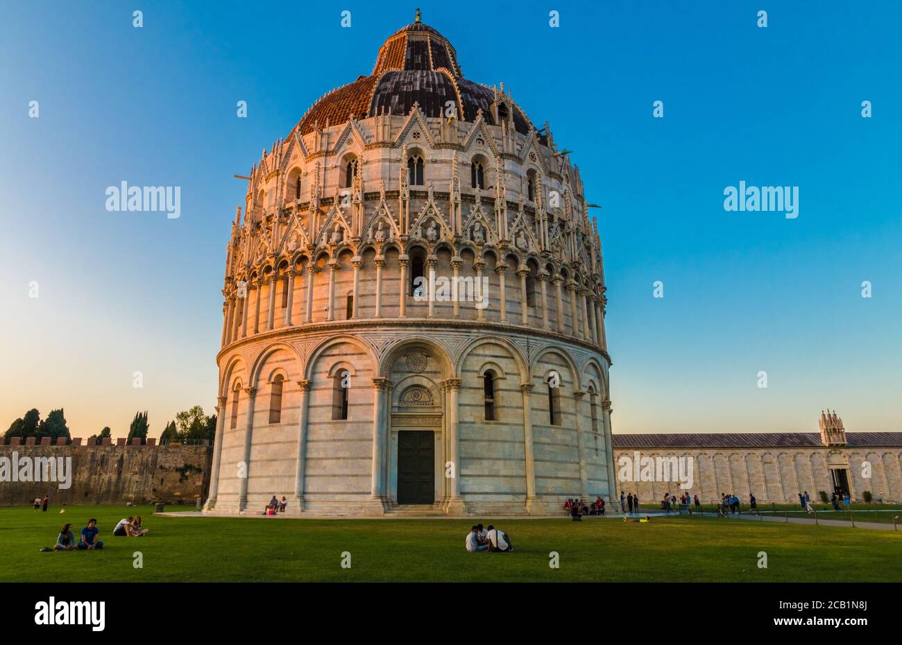 Herrliche Landschaft Aufnahme des berühmten Baptisterium von Pisa St. John. Auf dem Rasen vor der römisch-katholischen Kirche sitzen die Menschen ... Stockfoto