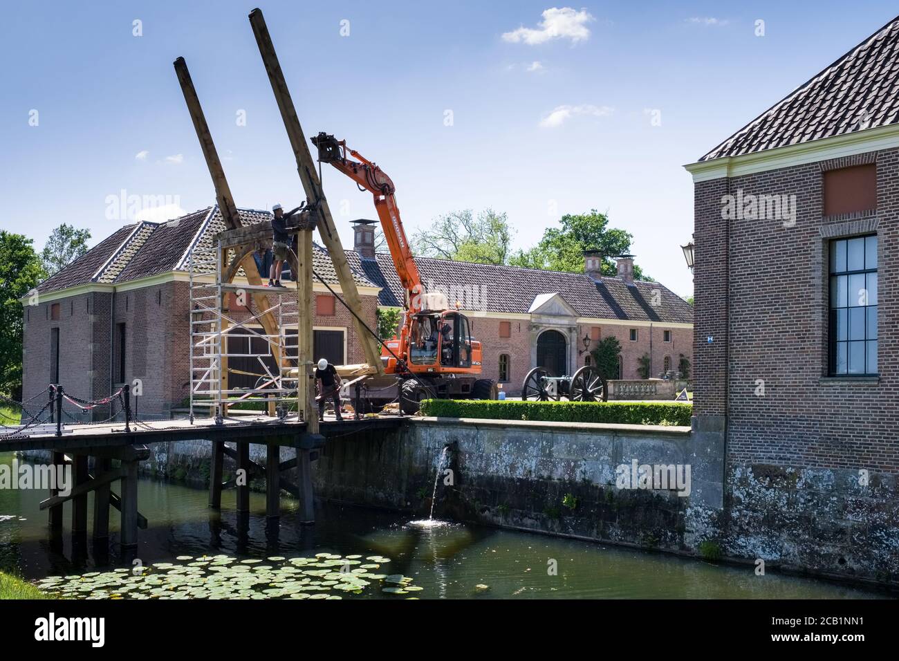 Bauarbeiter mit Mobilkran und Greifer reparieren die hölzerne Zugbrücke auf der berühmten spätmittelalterlichen Burg 'Twickel' in der Nähe von Delden, Niederlande Stockfoto