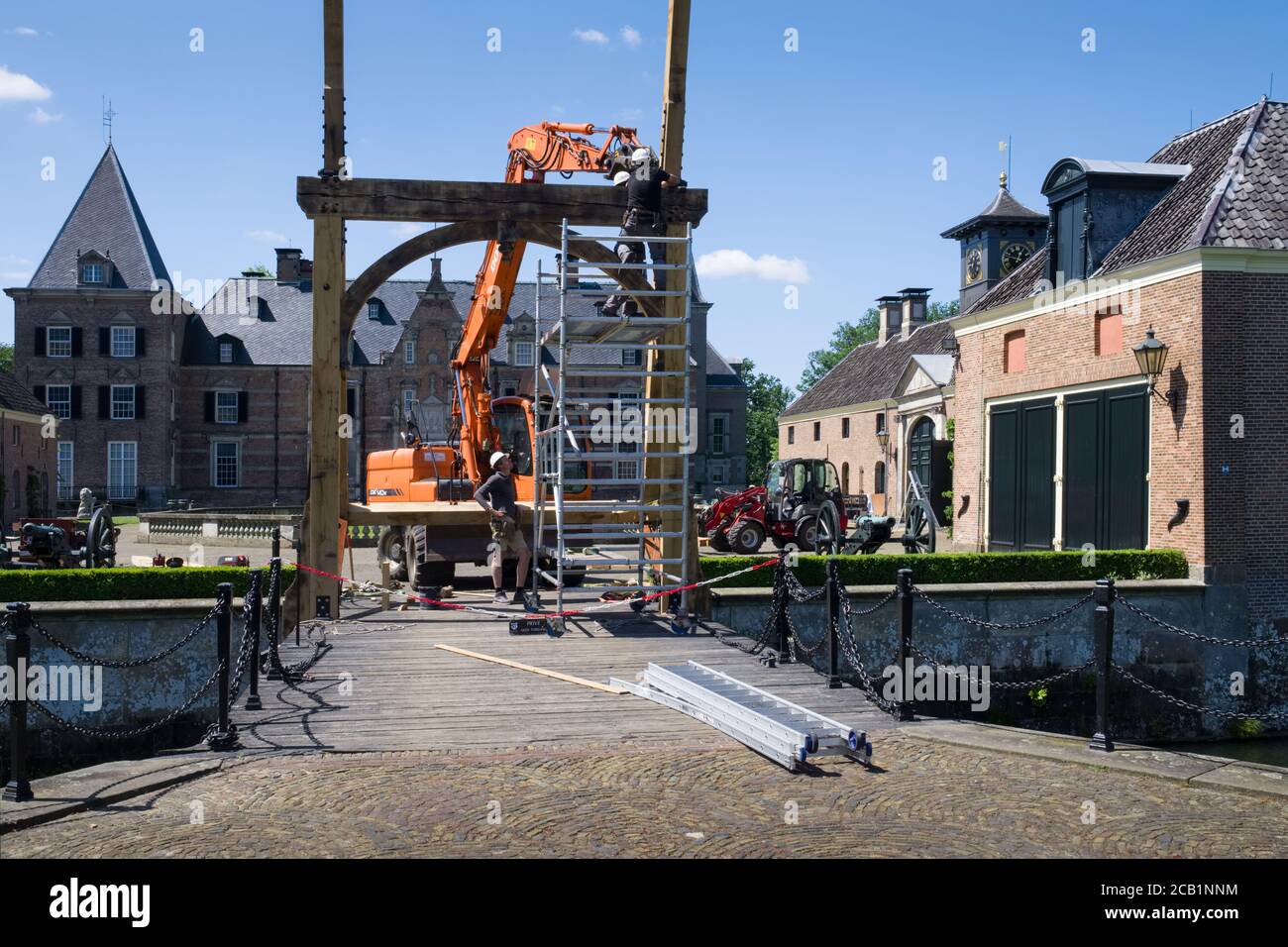 Bauarbeiter mit Mobilkran und Greifer reparieren die hölzerne Zugbrücke auf der berühmten spätmittelalterlichen Burg 'Twickel' in der Nähe von Delden, Niederlande Stockfoto