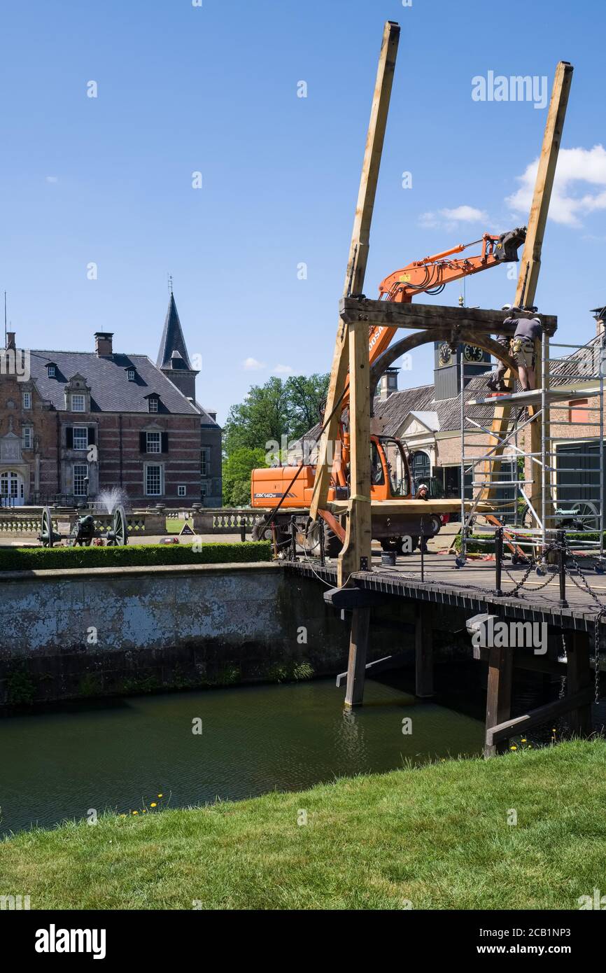 Bauarbeiter mit Mobilkran und Greifer reparieren die hölzerne Zugbrücke auf der berühmten spätmittelalterlichen Burg 'Twickel' in der Nähe von Delden, Niederlande Stockfoto