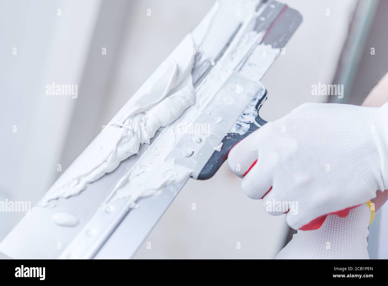 Close View Of Hand Holding Taping Knife With Drywall Compound On And Getting Ready To Patch Walls. Stockfoto