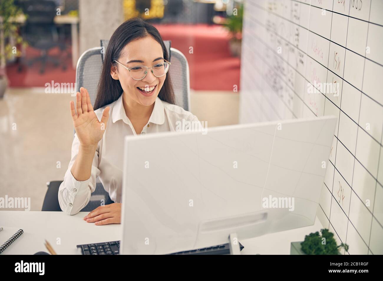 Positiv erfreut junge weibliche Person winkt ihre Hand Stockfoto