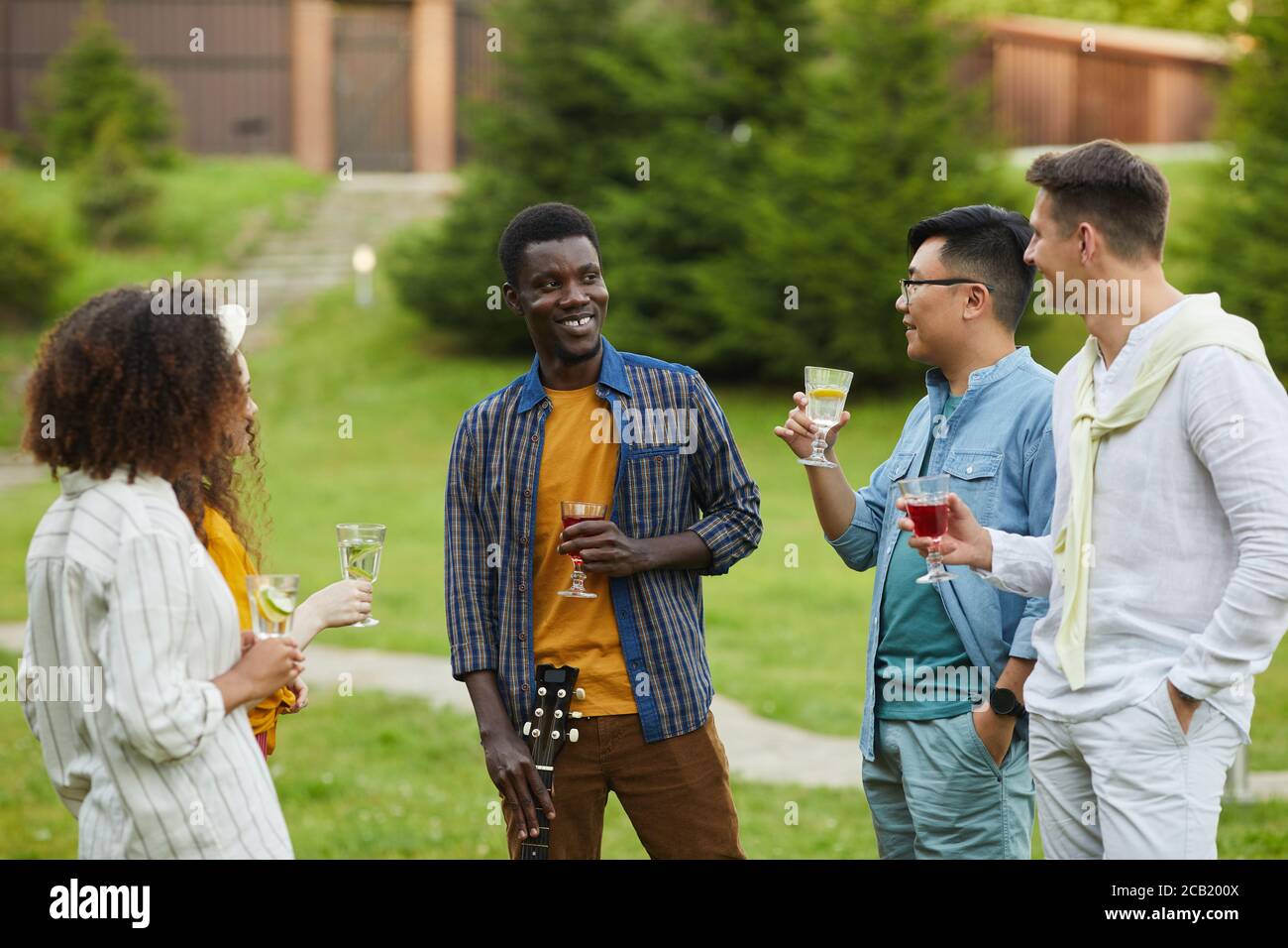 Multi-ethnische Gruppe von Menschen trinken Cocktails und plaudern, während draußen Party im Sommer genießen, kopieren Raum Stockfoto