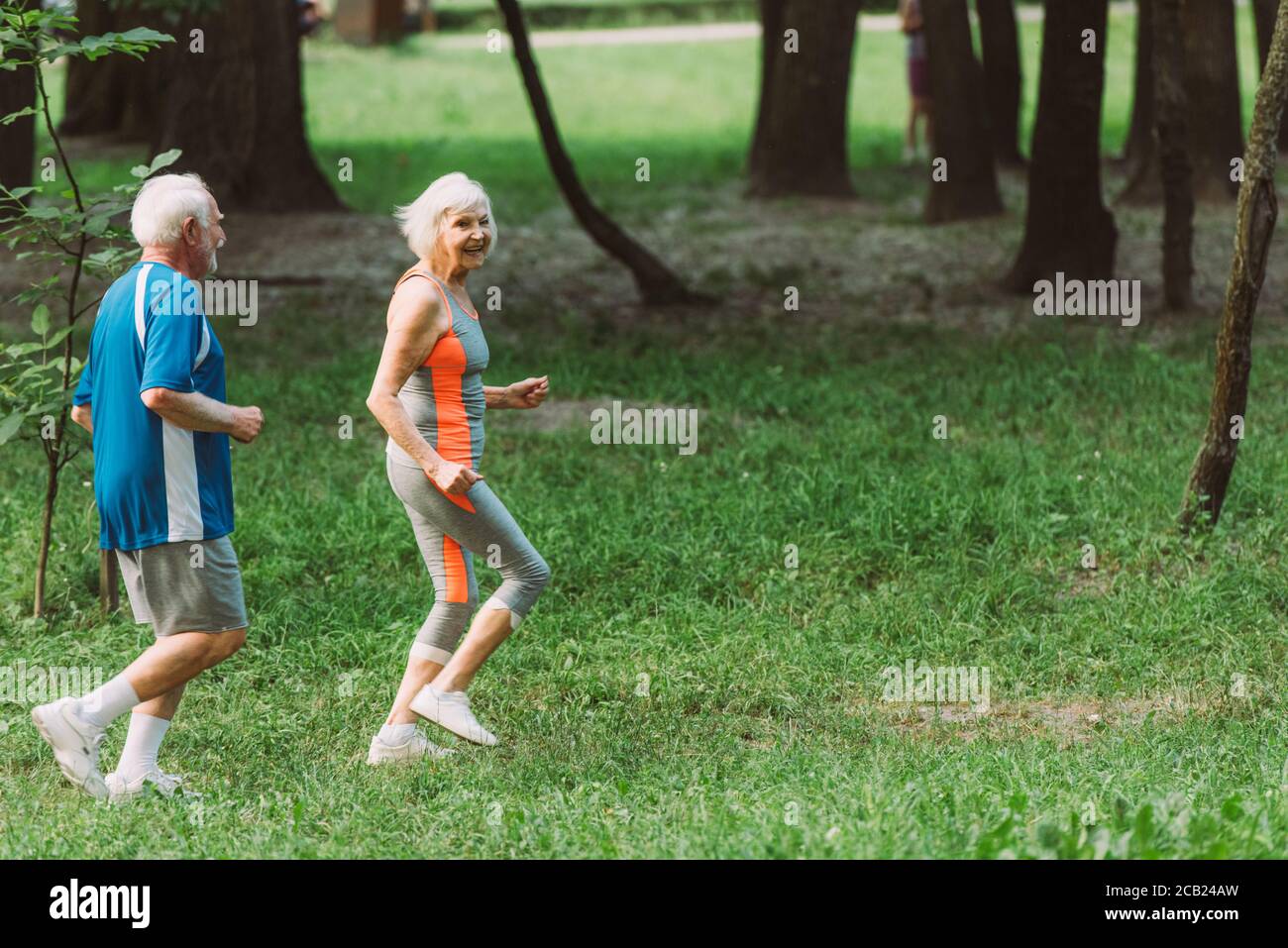Lächelnde ältere Frau läuft mit Mann im Park Stockfoto