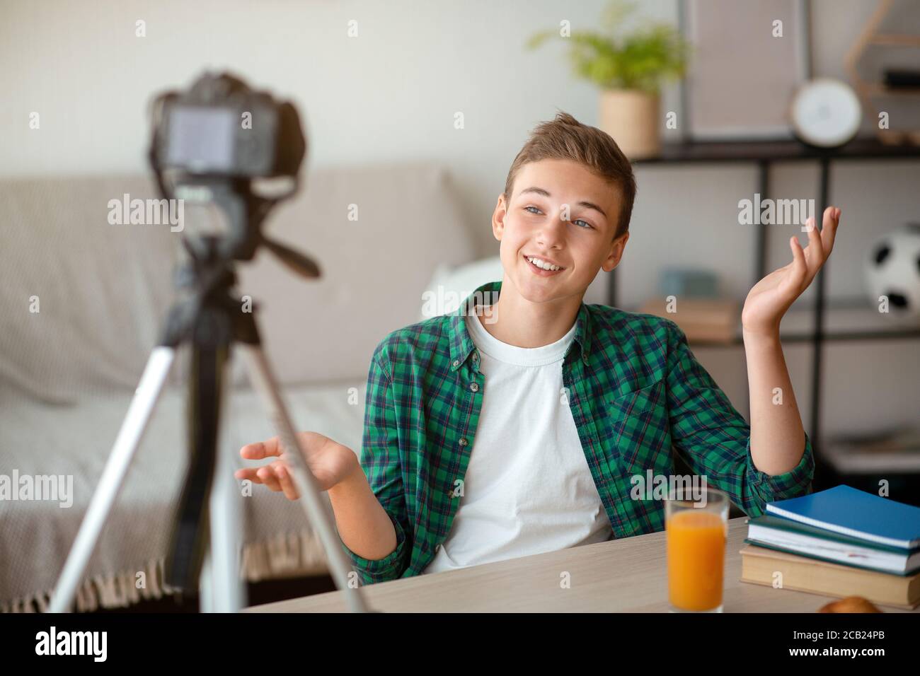 Fröhlicher Teenager sendet von zu Hause aus und teilt seine Gedanken mit Anhängern Stockfoto