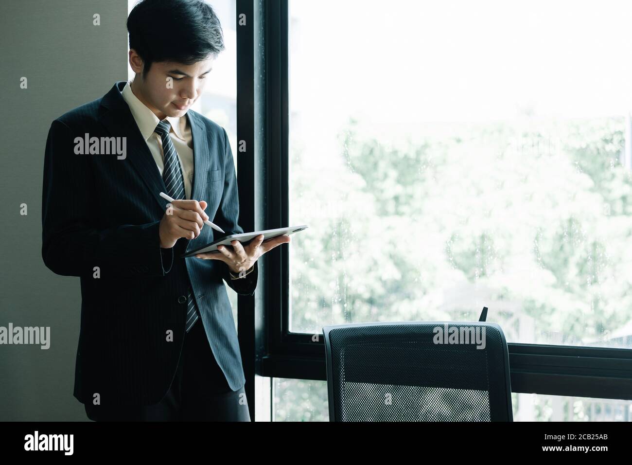 Junge asiatische Geschäftsmann stehen und mit Tablet im Büro Stockfoto