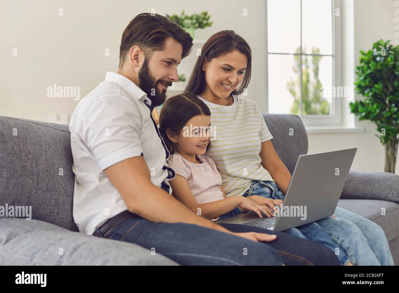 Glückliche Familie mit Laptop, die online im Online-Shop unterwegs zu Hause einkaufen. Stockfoto