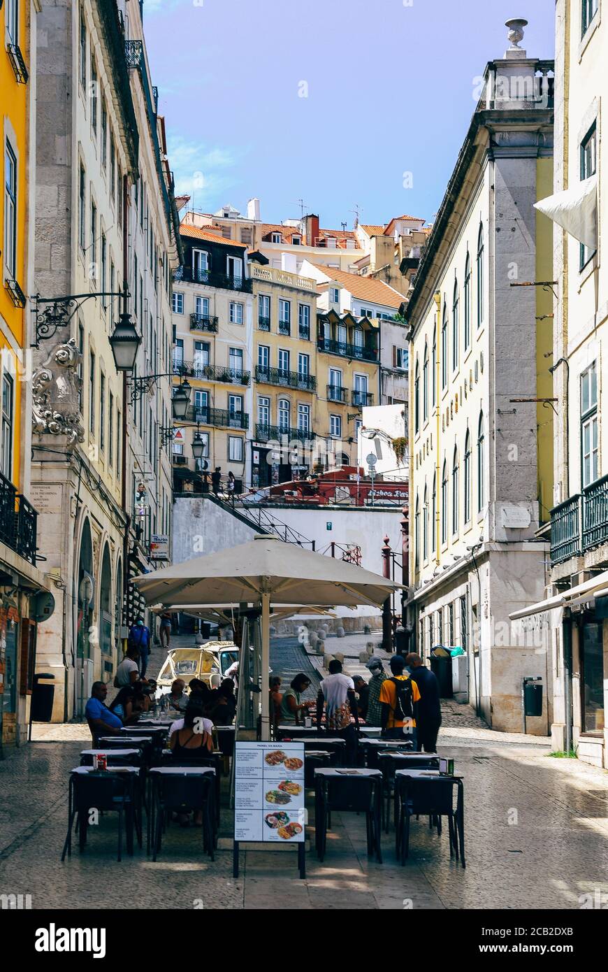 Café und Restaurant im belebten historischen Zentrum Baixa District. Perspektivischer Blick auf die Straße von Geschäften und Cafés in traditionellen alten Gebäuden Stockfoto