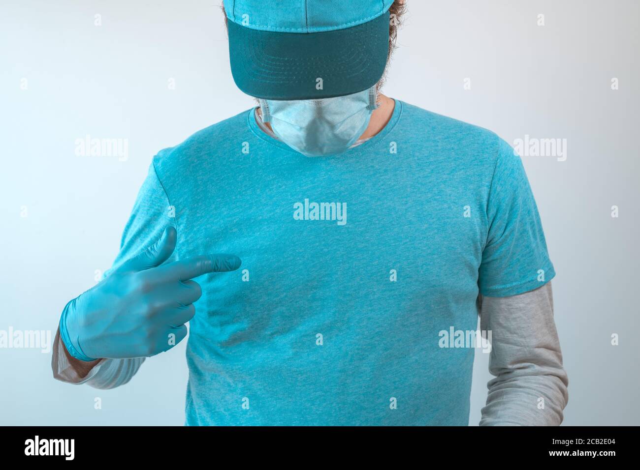 Delivery Mann mit schützender Arbeitskleidung trägt blaue T-Shirt-Modell, blaue Baseball-Kappe und Schutzhandschuhe auf Brust zeigen Stockfoto