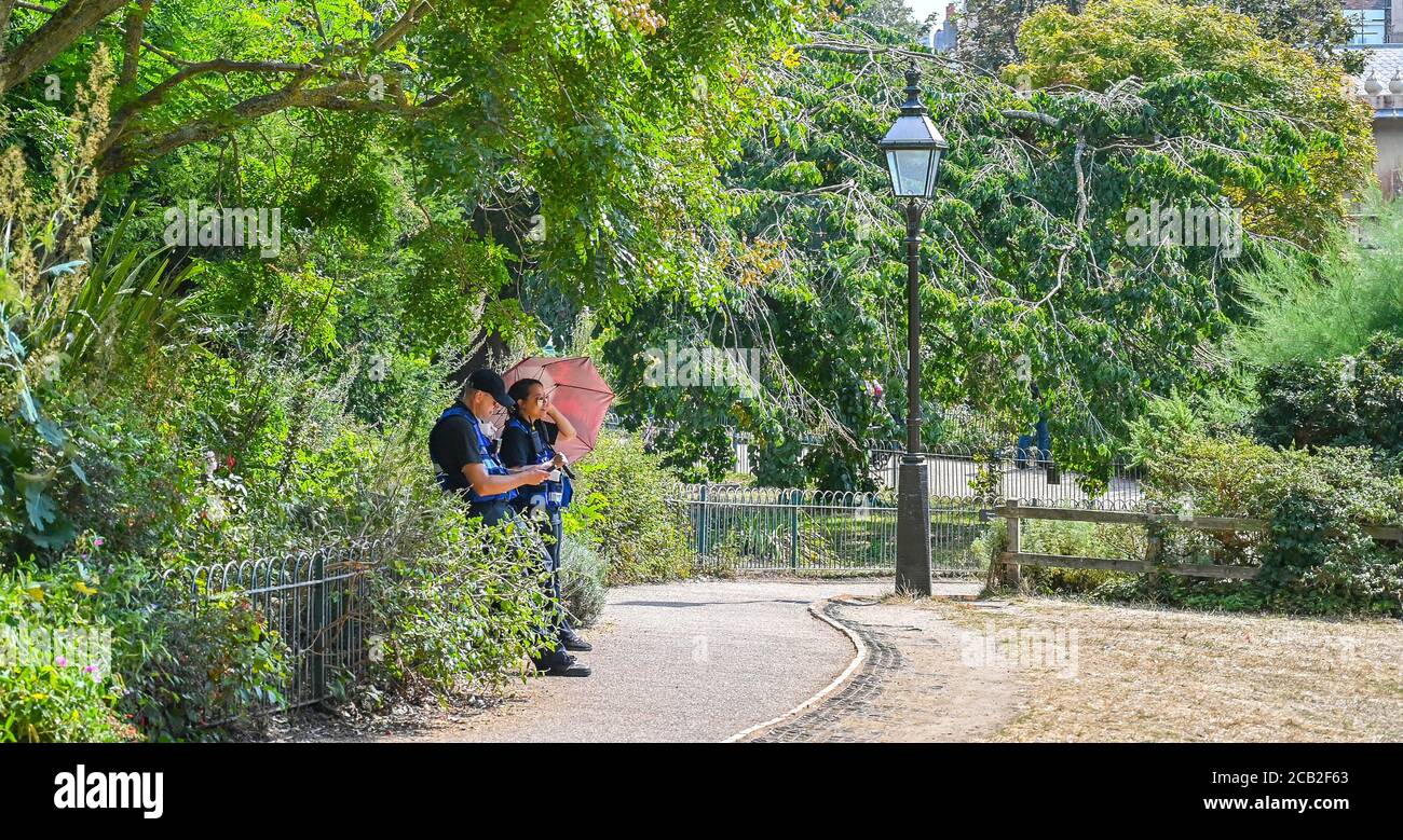 Brighton UK 10. August 2020 - Sicherheitspersonal findet Schatten in Pavilion Gardens Brighton an einem heißen, sonnigen Tag, wenn die Temperaturen in Teilen des Südostens wieder bis in die 30er Jahre reichen : Credit Simon Dack / Alamy Live News Stockfoto