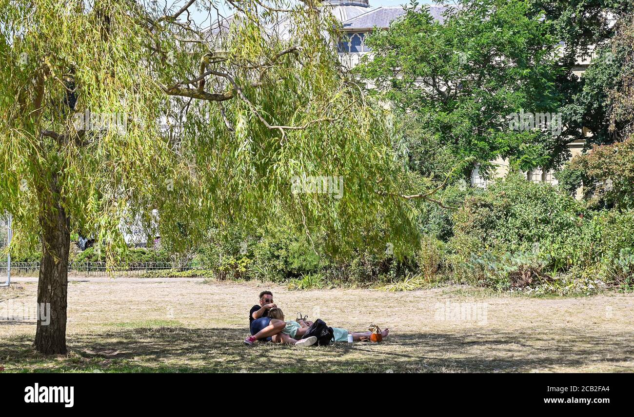 Brighton UK 10. August 2020 - Dieses junge Paar findet Schatten unter einem Baum in Pavilion Gardens Brighton an einem heißen, sonnigen Tag, wenn die Temperaturen in Teilen des Südostens wieder bis in die 30er Jahre reichen : Credit Simon Dack / Alamy Live News Stockfoto