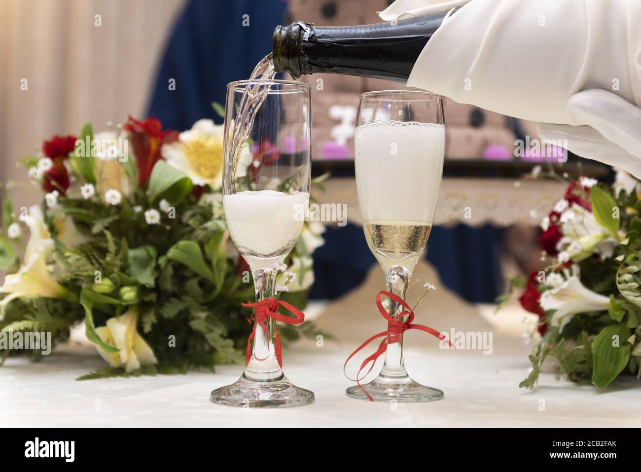 Während einer Hochzeit gießt der Kellner Champagner auf die Gläser Stockfoto