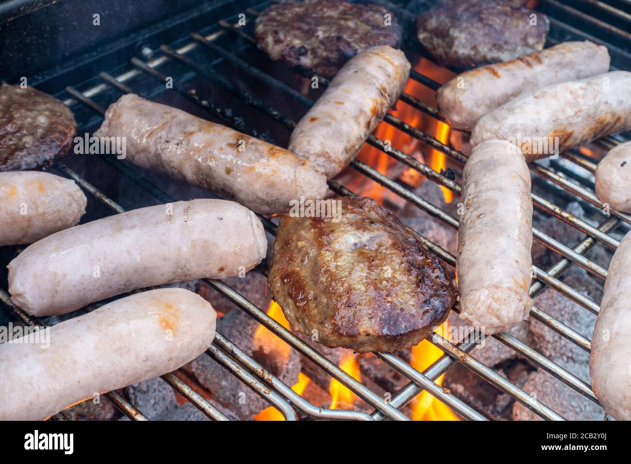 Würstchen und Rindfleisch Burger Kochen auf einem Grill. Stockfoto