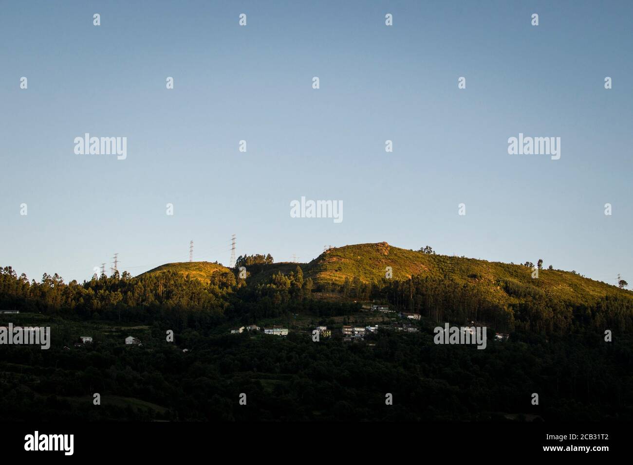 Ein Hügel mit Dorfhäusern, die bei Sonnenuntergang von der Sonne erleuchtet werden, am Ende des Tages Stockfoto