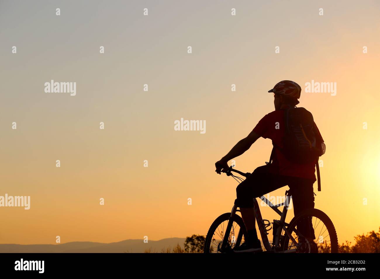 Symbolbild: Silhouette eines Mountainbiker an einem warmen Sommerabend (Model erschienen) Stockfoto