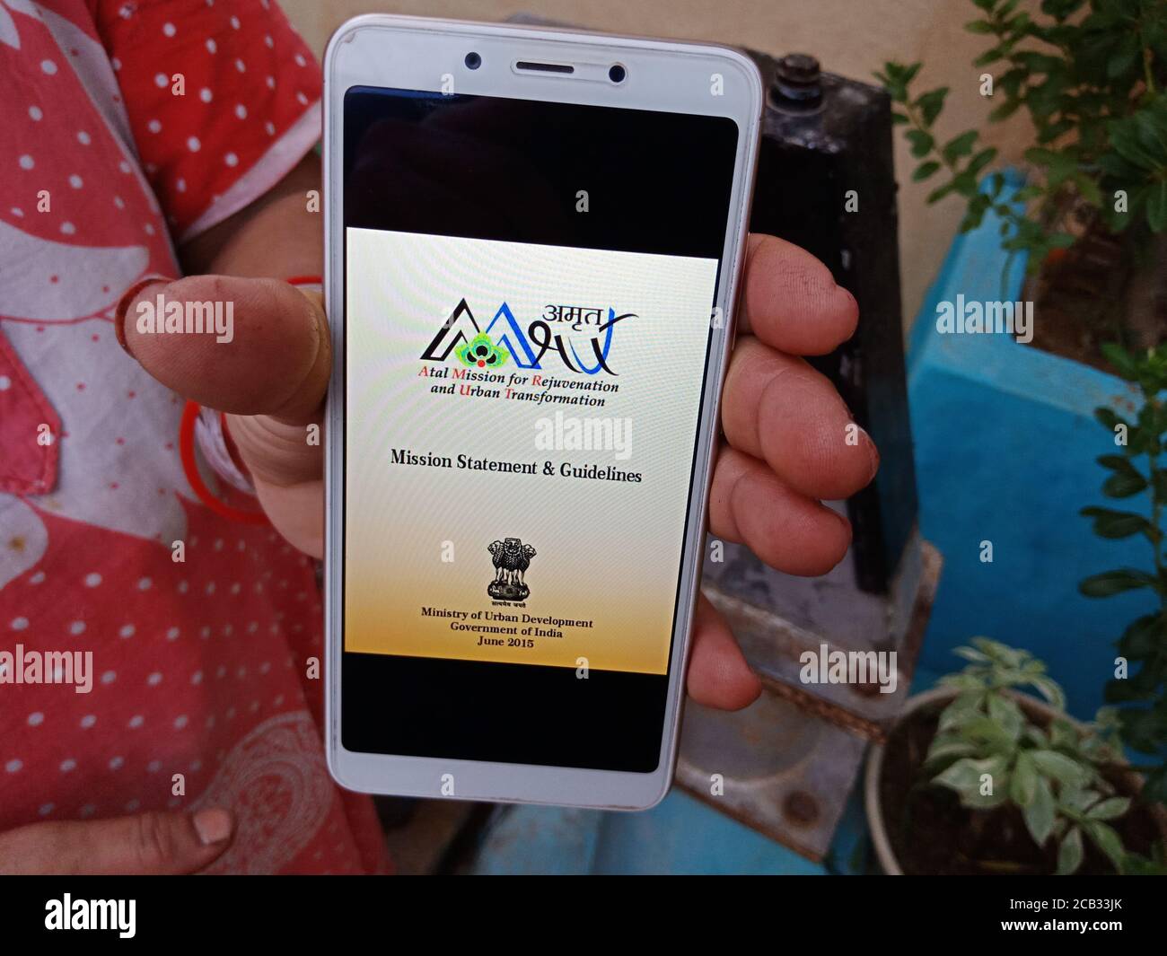 DISTRICT KATNI, INDIEN - 23. MAI 2020: Frau hält Smartphone mit angezeigt atal Mission für Verjüngung und urbane Transformation Schema auf dem Bildschirm Stockfoto