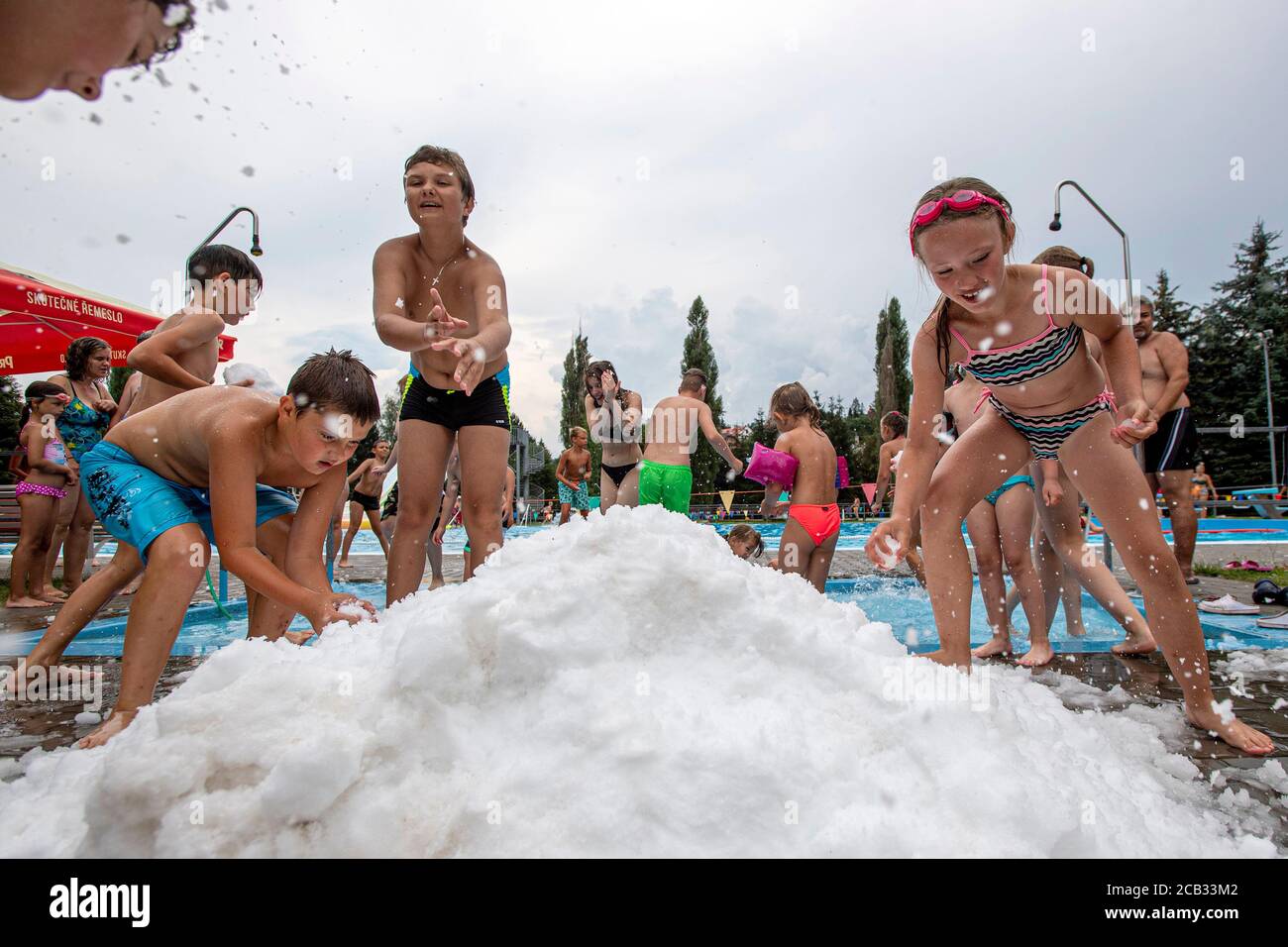 Die Besucher des Schwimmbads in Nachod genießen Spaß während des Schneeballens. Die Mitarbeiter des Schwimmbades werden am 10. August 2020 den Schnee vom örtlichen Eisstadion in Nachod, Tschechien, transportieren. (CTK Photo/David Tanecek)--- Stockfoto