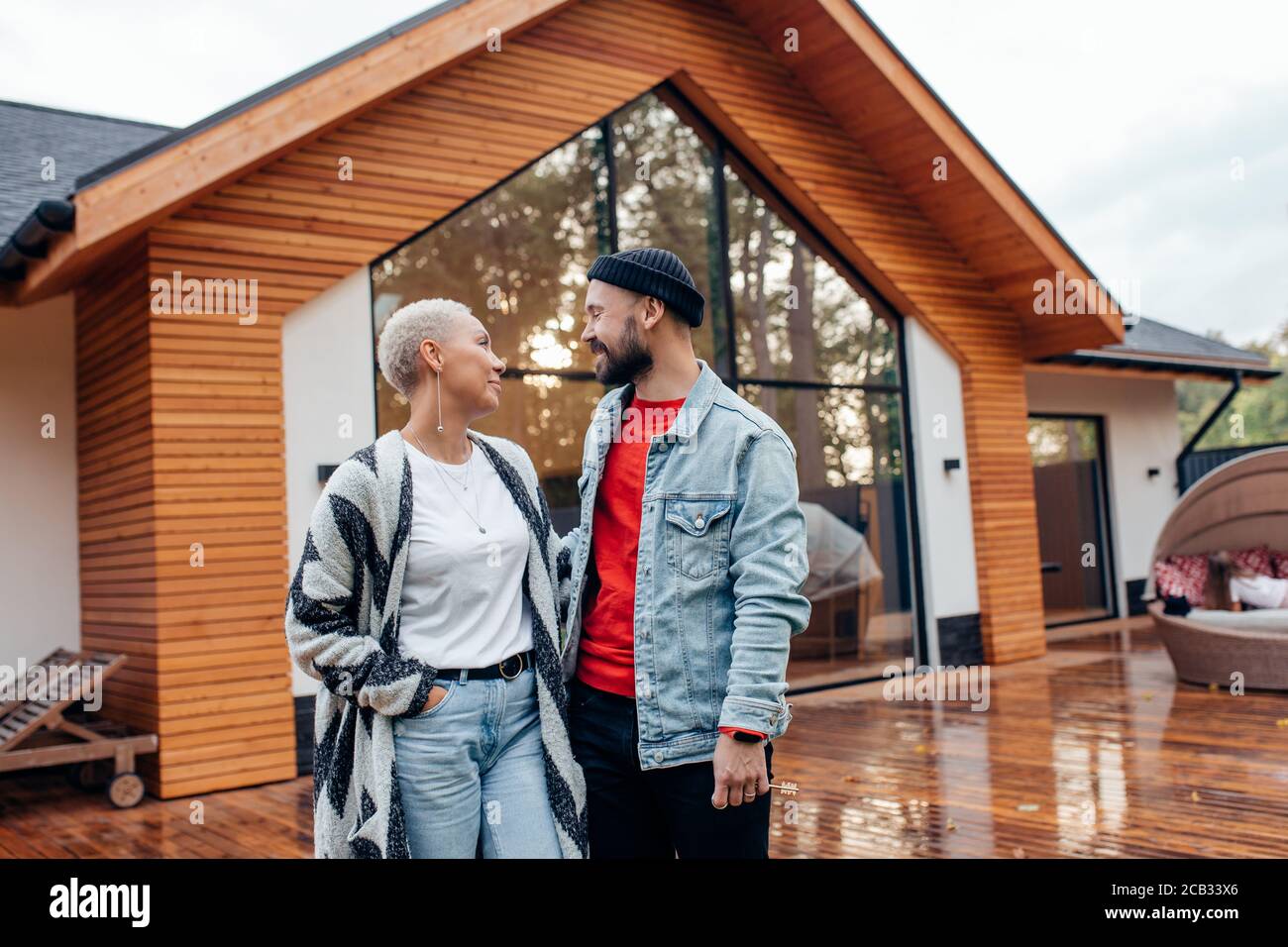 Junge kaukasische Paar schauen einander mit Liebe. Hintergrund Holz Landhaus Stockfoto