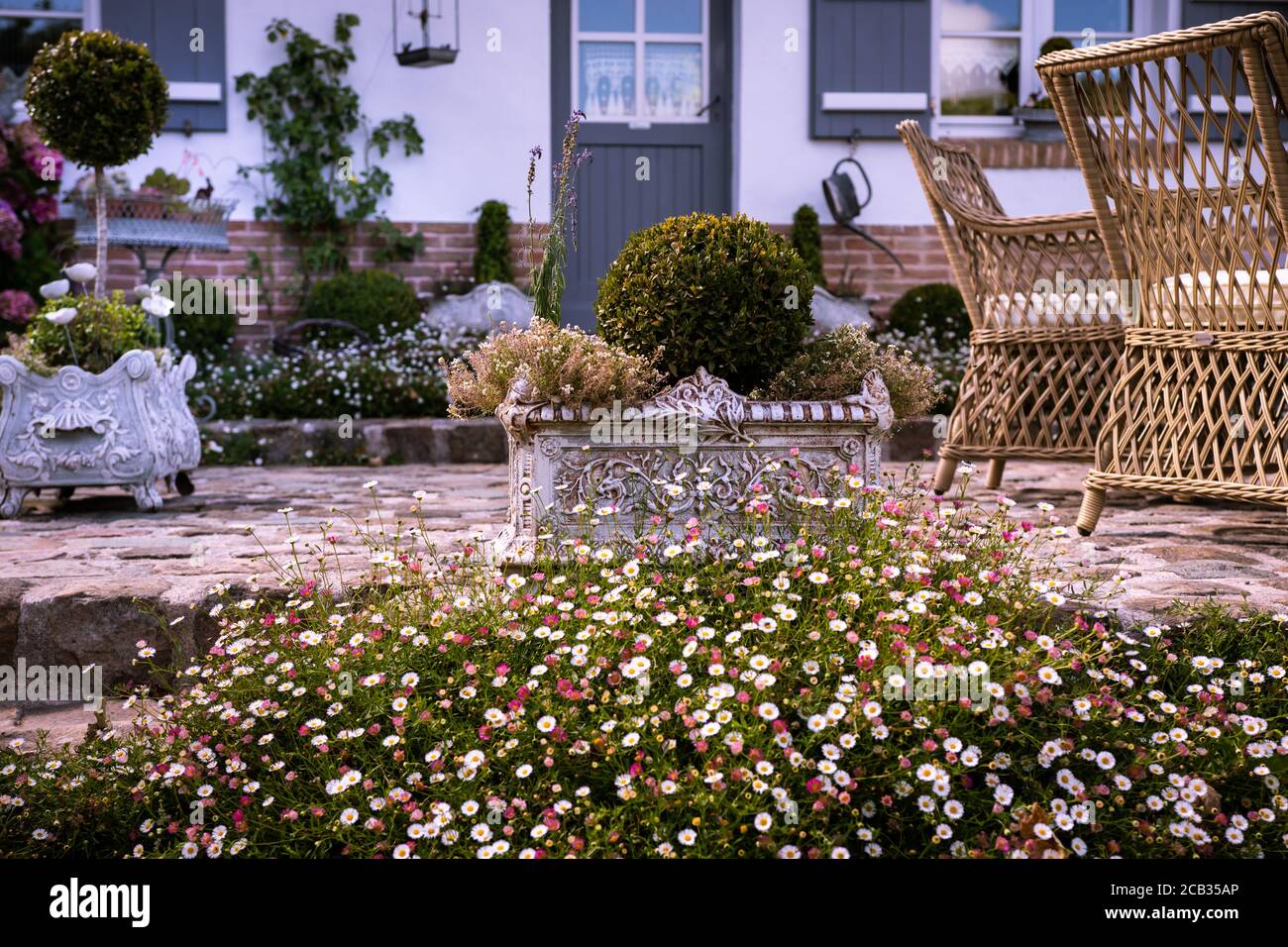 Haus mit gepflasterter Terrasse und Blumen Stockfoto