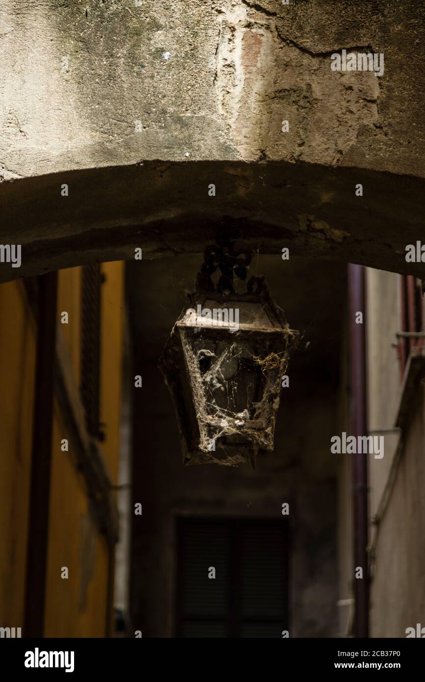 Eine alte Straßenbeleuchtung, bedeckt mit Spinnweben in einer der vielen dunklen, engen Straßen in der antiken Stadt Bevagna, Umbrien, Italien Stockfoto