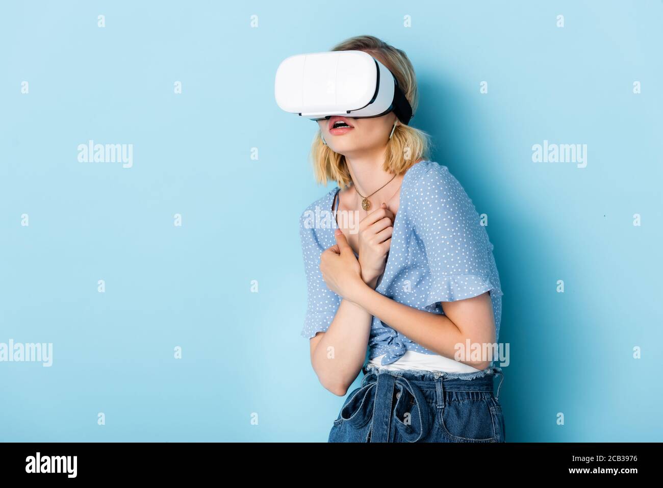 Junge und verängstigte Frau in Virtual-Reality-Headset auf blau Stockfoto