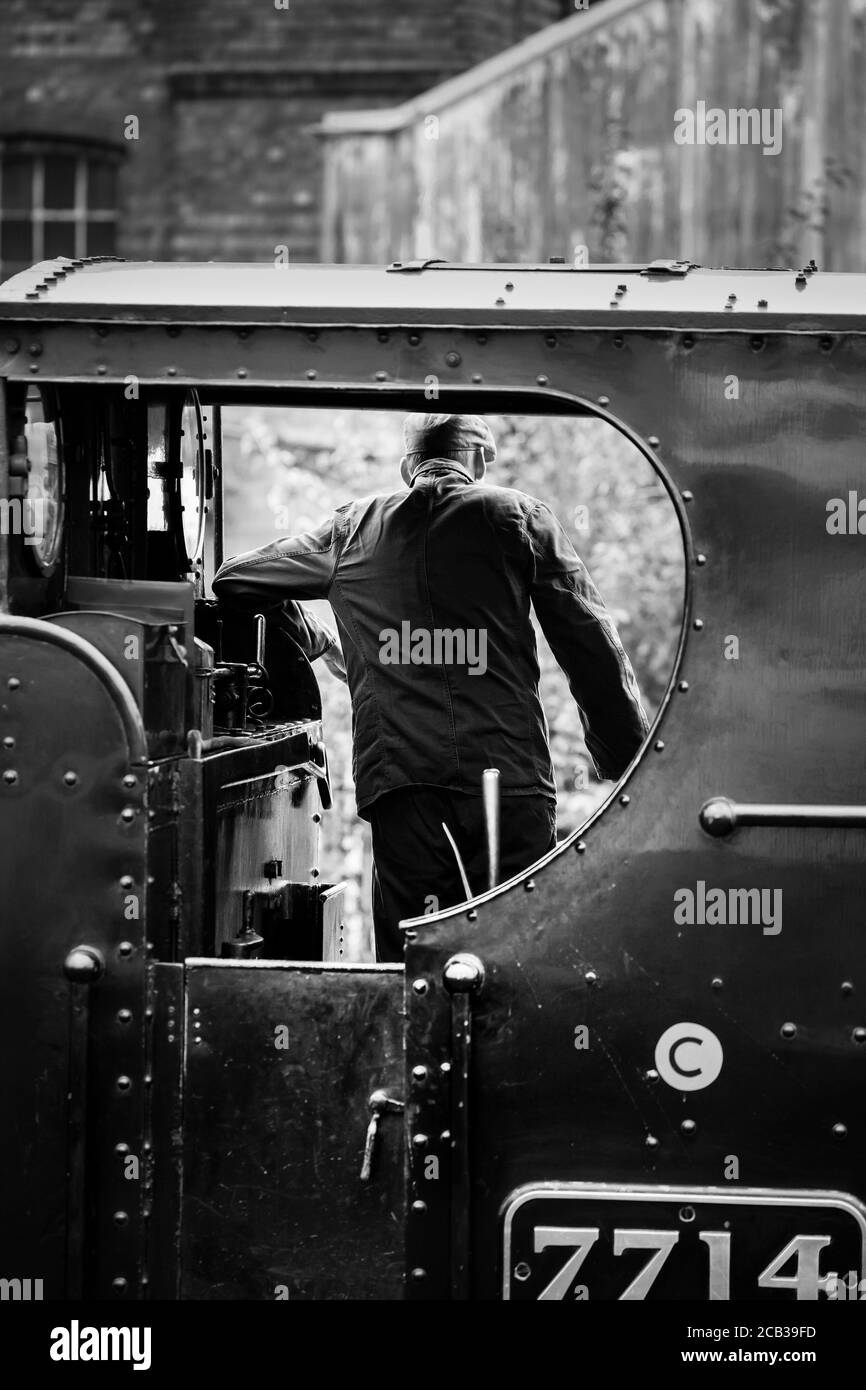 Monochrome Rückansicht des Dampflokomotive-Fahrers in der Motorkabine, der die Abfahrt auf der Severn Valley Railway Heritage Line, Großbritannien, erwartet. Stockfoto
