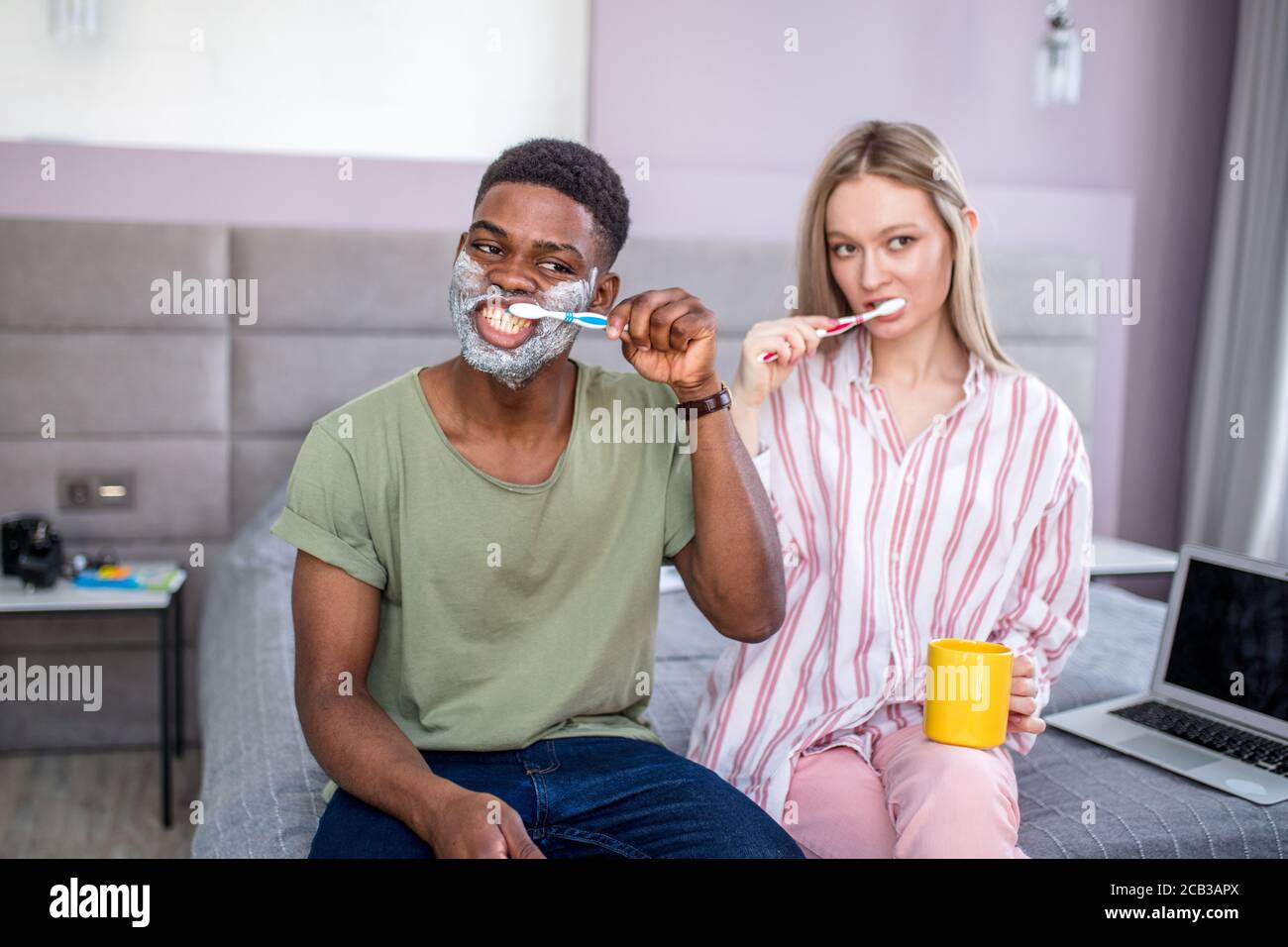 Attraktive multiethnischen Paar ihre Zähne putzen morgens zu Hause, afrikanischer Mann in Rasierschaum auf seine Wangen Stockfoto
