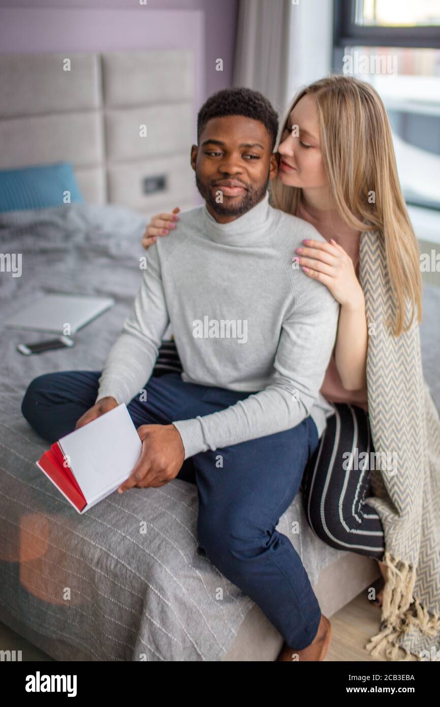 Lächelnd romantische multiethnischen paar Ausgaben zusammen kalten Wochenende zu Hause, genießen, zusammen lesen das gleiche Buch Stockfoto